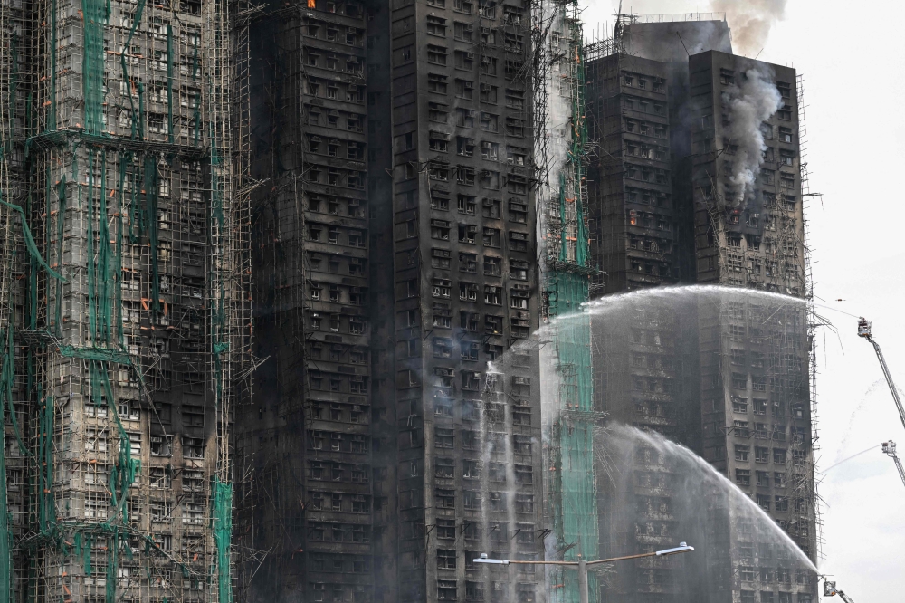 Firefighters spray water on flames as a major fire burns through several apartment blocks at the Wang Fuk Court residential estate on November 27, 2025. (Photo by Peter Parks / AFP)