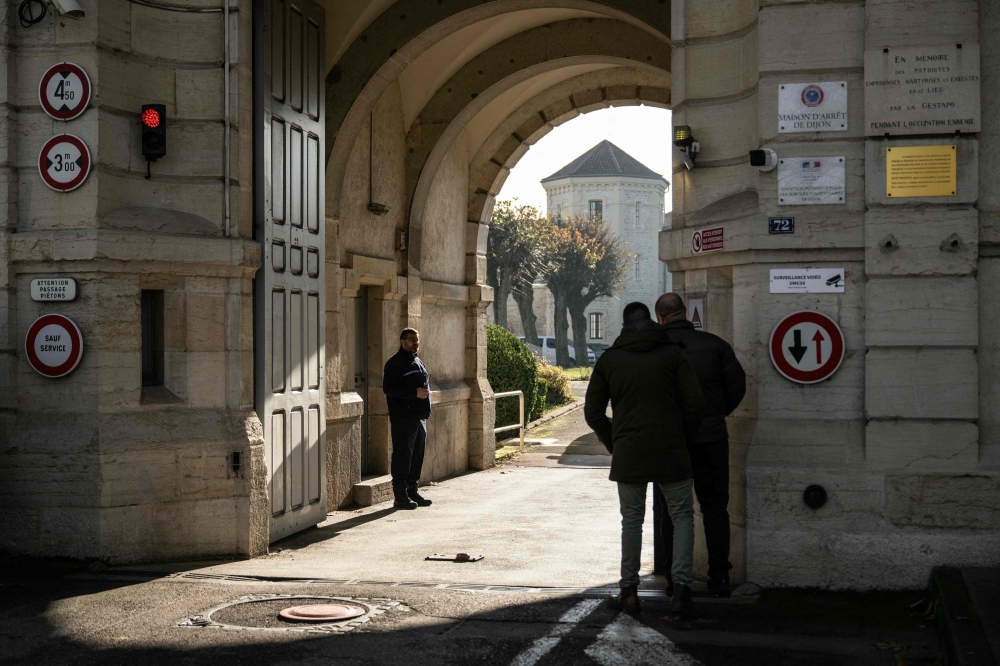 A member of the prison staff stands behind the entrance door of the jail of Dijon central eastern France on November 27, 2025. (Photo by Arnaud Finistre / AFP)