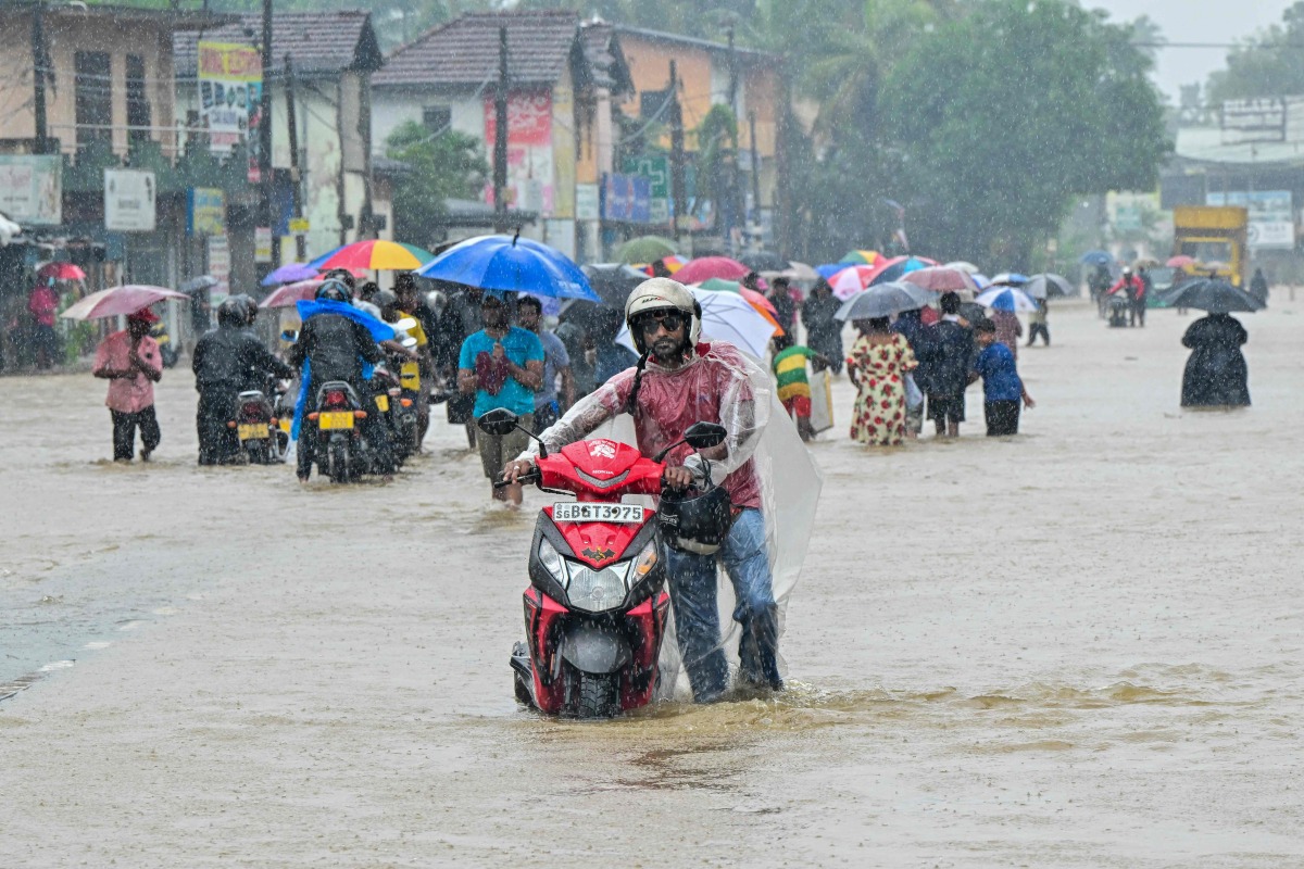 People wade through a flooded road after heavy rainfall in Kaduwela on the outskirts of Colombo on November 28, 2025. (Photo by Ishara S. KODIKARA / AFP)
