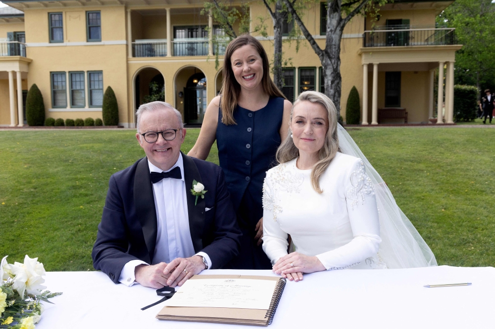Australia Prime Minister Anthony Albanese (L) and his new wife Jodie Haydon (R) sign the marriage certificate with celebrant Bree during their wedding ceremony in Canberra on November 29, 2025. (Photo by Mike Bowers / AFP)