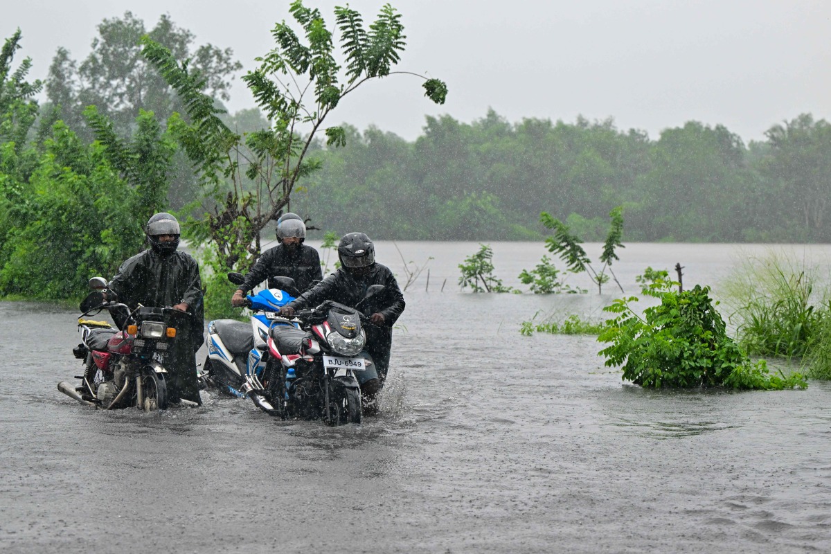 Motorists wade through a flooded street in Biyagama on the outskirts of Colombo on November 28, 2025. (Photo by Ishara S. KODIKARA / AFP)