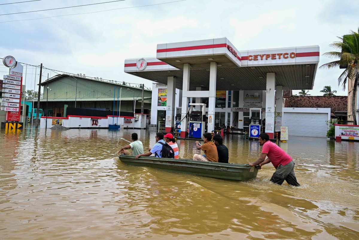 People ride a boat across a flooded street in Ambatale on the outskirts of Colombo on November 29, 2025. (Photo by Ishara S. KODIKARA / AFP)