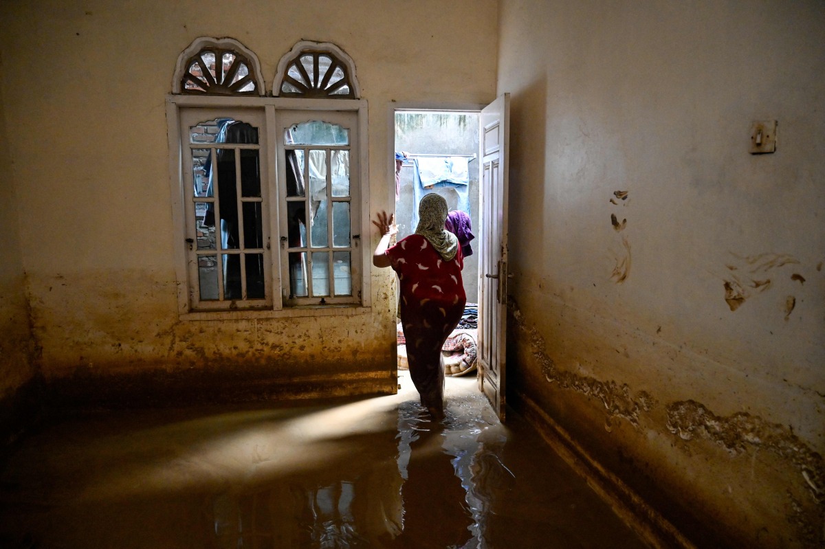 A woman inspects her damaged house after the flash floods in Meureudu, Pidie Jaya district of Indonesia's Aceh province, on November 28, 2025. (Photo by Chaideer MAHYUDDIN / AFP)
