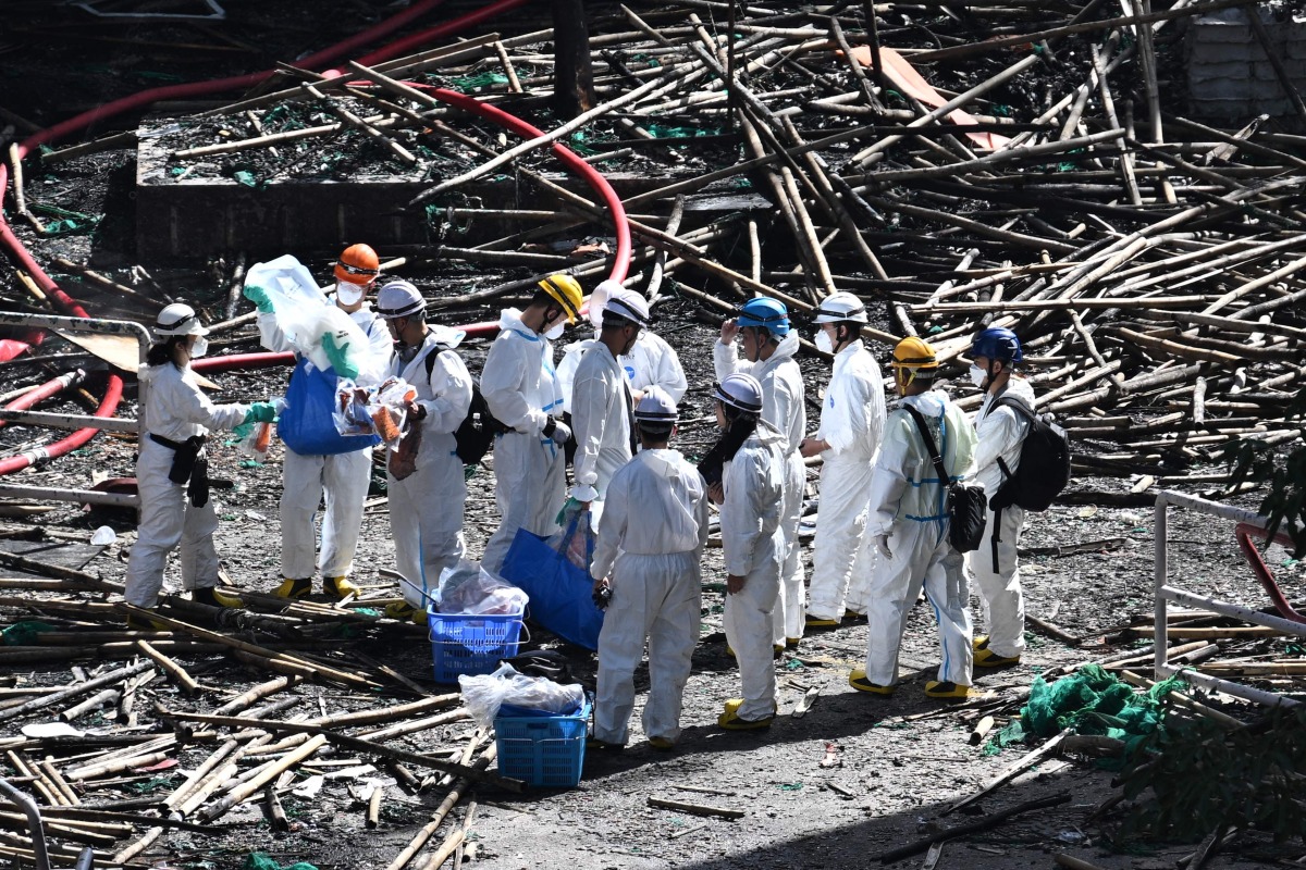 Police officers from the Disaster Victim Identification Unit (DVIU), dressed in white-coloured full-body protective gear, enter one of the housing blocks of Wang Fuk Court in the aftermath of the deadly November 26 fire, in Hong Kong on November 29, 2025. (Photo by Philip FONG / AFP)

