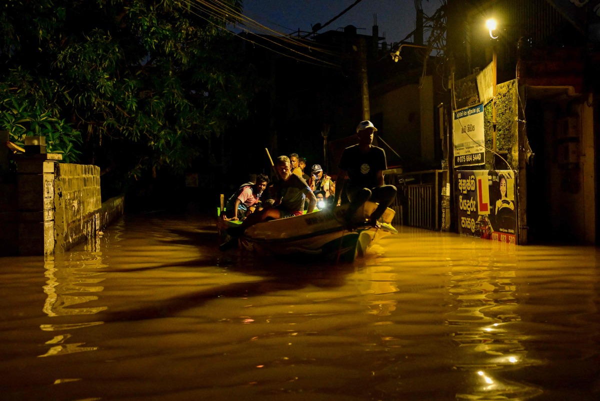 People ride on a boat belonging to Sri Lanka's army at a flooded street after heavy rainfall in Wellampitiya on the outskirts of Colombo on November 30, 2025. (Photo by Ishara S. KODIKARA / AFP)
