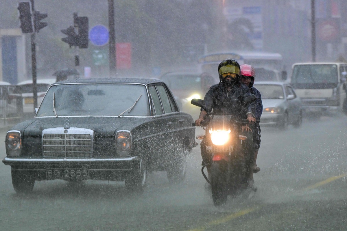 Commuters drive through a flooded street amid heavy rains in Colombo on December 5, 2025. (Photo by Ishara S. KODIKARA / AFP)
