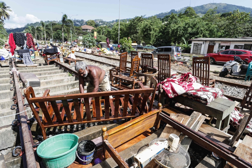 A flood victim restores his belongings in the aftermath of Cyclone Ditwah, along railway tracks in Kandy on December 6, 2025. (Photo by AFP)