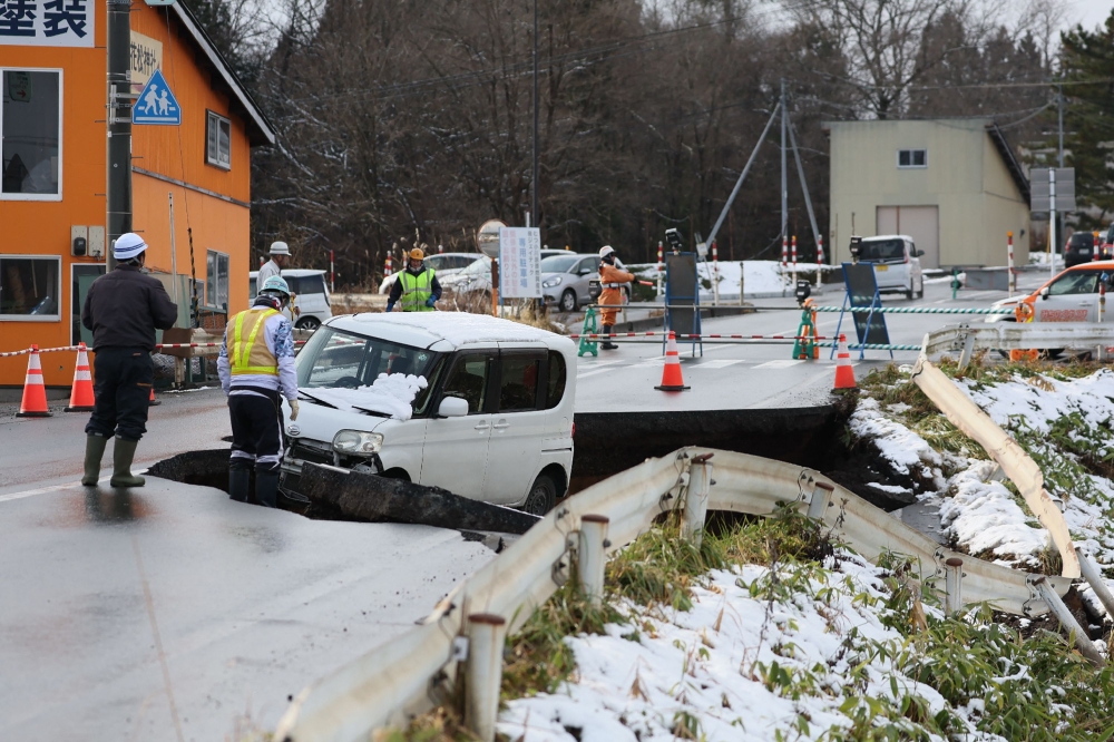 A vehicle is seen on a collapsed road in Tohoku town in Aomori Prefecture on December 9, 2025, following a 7.5 magnitude earthquake off northern Japan. (Photo by JIJI Press / AFP)