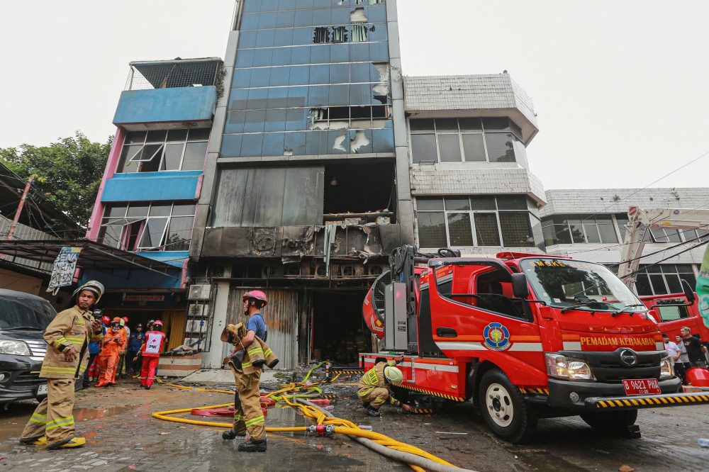 Firefighters are seen at the scene where they have extinguished a fire that killed at least 20 people at a seven-storey building in central Jakarta on December 9, 2025. (Photo by Synatria Respati / AFP)