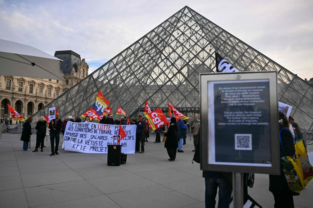 Members of the French CGT union protest outside the entrance to the Louvre Museum as workers voted to go on strike in Paris on December 15, 2025. (Photo by Blanca Cruz / AFP)