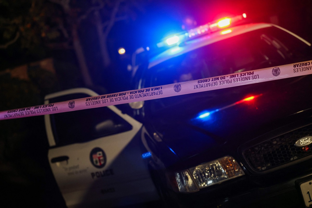 A Los Angeles Police Department patrol car is seen behind police tape blocking the access to a house in the Brentwood neighborhood of Los Angeles, California, on December 14, 2025. (Photo by Michael Tran / AFP)
