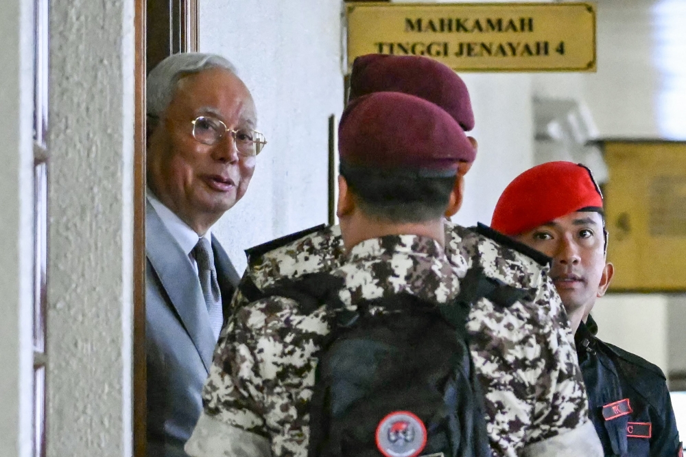 Former prime minister of Malaysia Najib Razak (L) arrives for a court hearing where he seeks to land a ruling allowing him to serve the rest of his six-year sentence under house arrest instead of in the Kajang Prison, at the Kuala Lumpur High Court in Kuala Lumpur on December 22, 2025. (Photo by Mohd Rasfan / AFP)