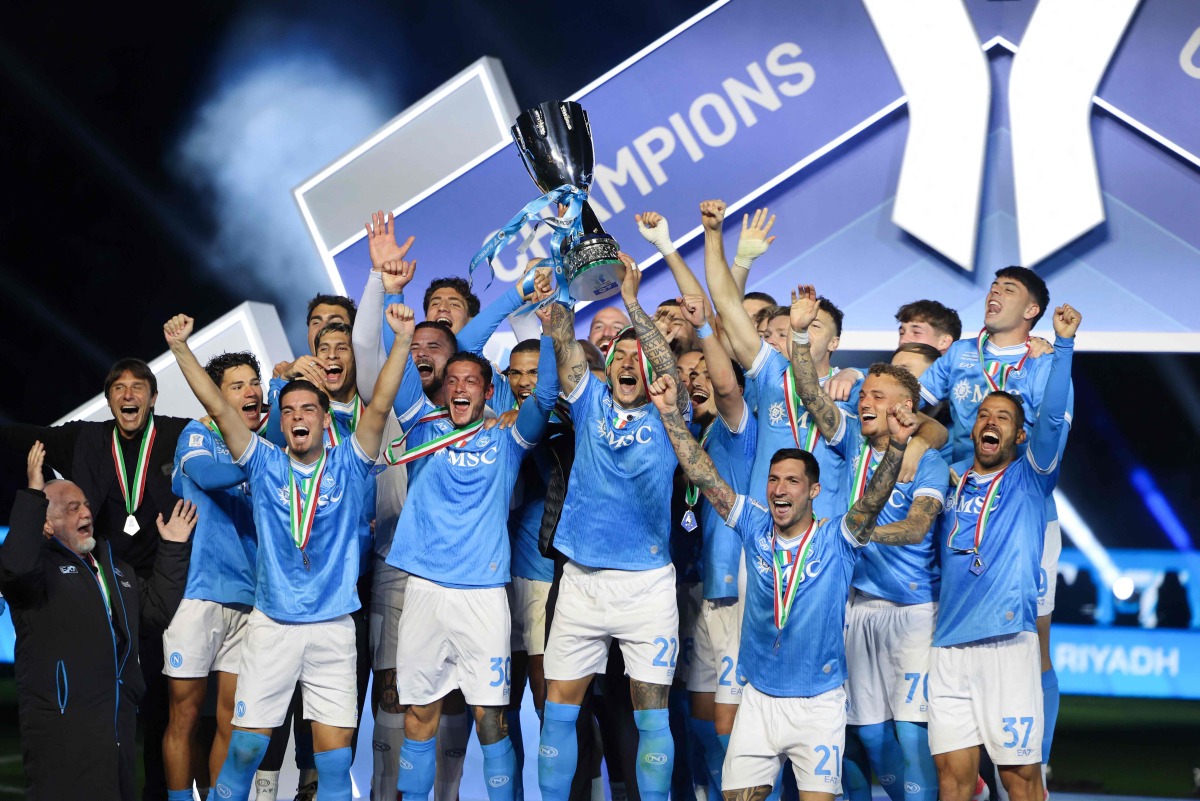 Napoli’s Giovanni Di Lorenzo lifts the trophy on the podium as team celebrates the triumph. 