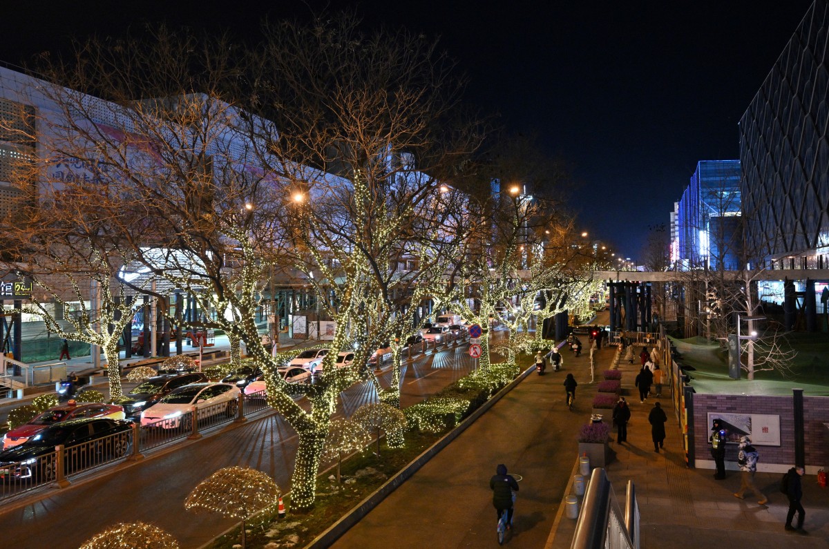 People walk next to shopping centers in Beijing on December 19, 2025. (Photo by Adek BERRY / AFP)
