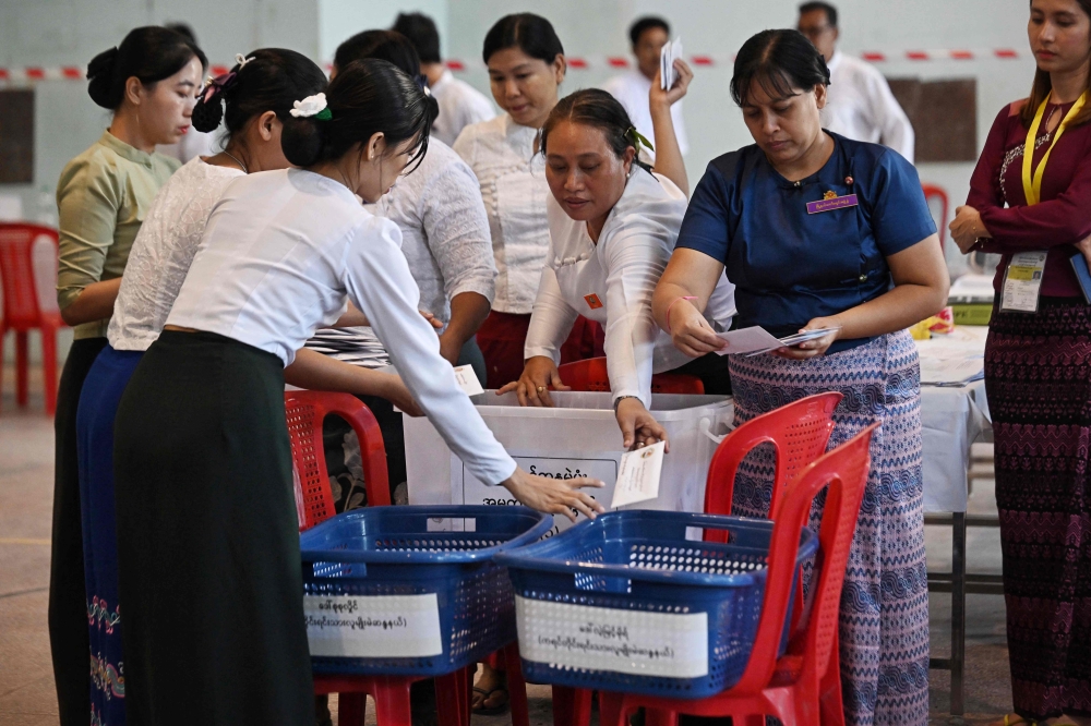 Members of Myanmar Union Election commission (UEC) count ballots after the closing of polls at a polling station in the first phase of Myanmar general election in Yangon on December 28, 2025. (Photo by Lillian Suwanrumpha/ AFP)