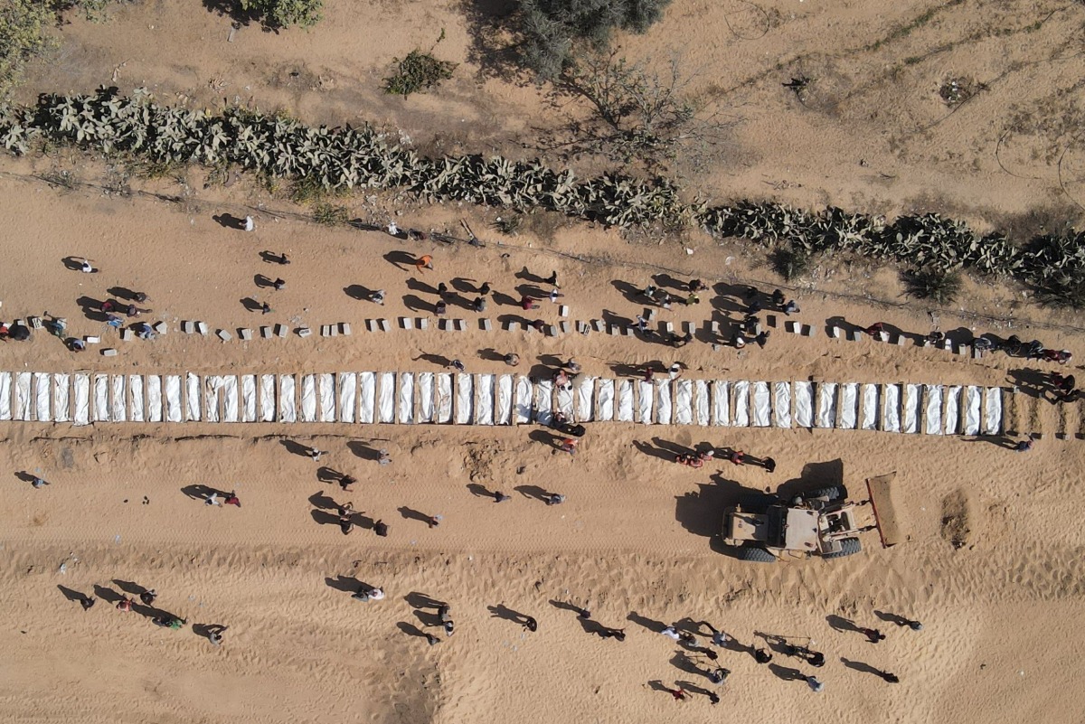 This aerial view shows Palestinians burying 54 unidentified bodies in a cemetery in Deir al-Balah, in the central Gaza Strip, on October 22, 2025. (Photo by AFP) / AFP PICTURES OF THE YEAR 2025