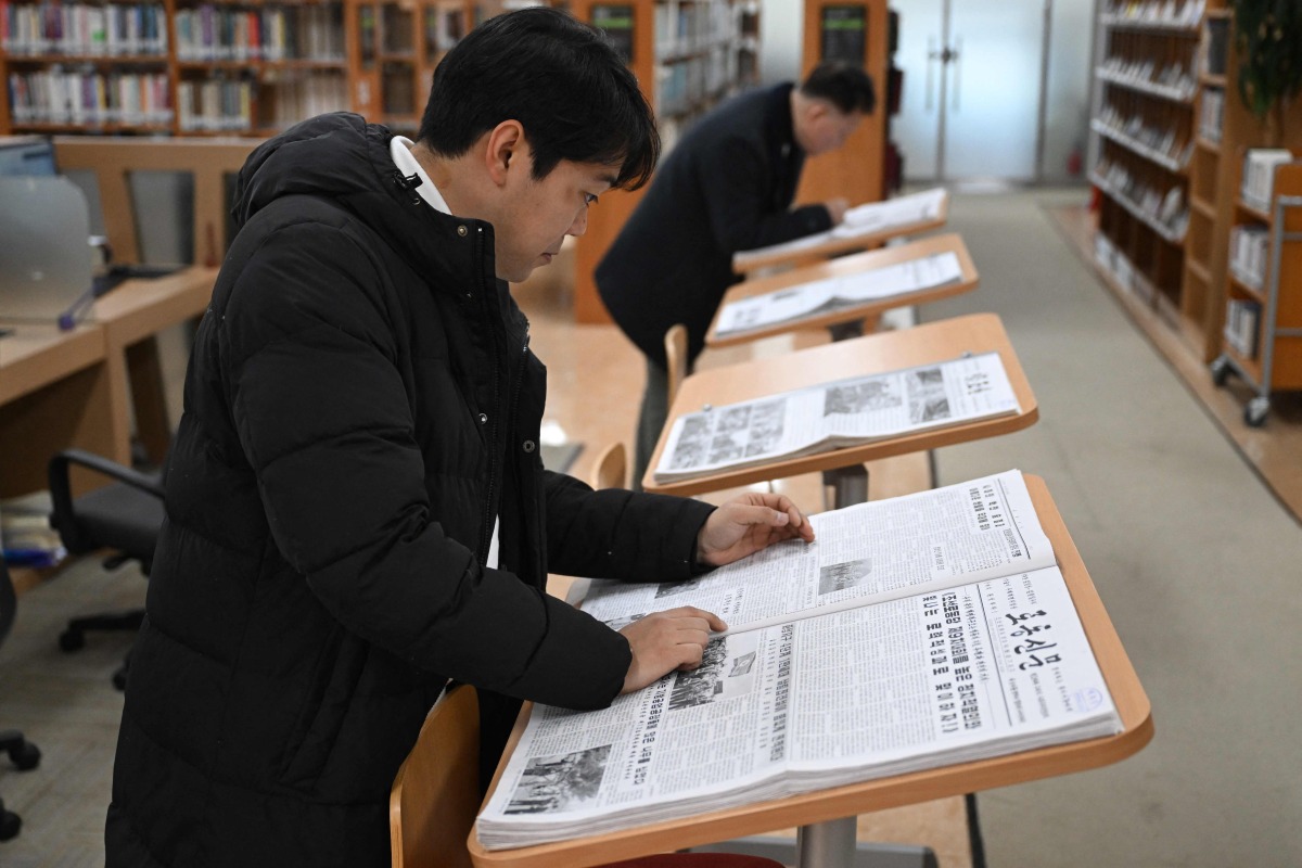 A visitor reads Rodong Sinmun (front), North Korea's top newspaper, at the National Library of Korea in Seoul on January 2, 2026. Photo by Jung Yeon-je / AFP