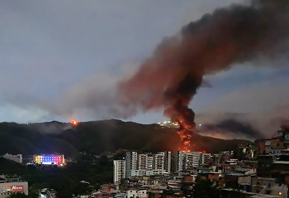 Fire at Fuerte Tiuna, Venezuela's largest military complex, is seen from a distance after a series of explosions in Caracas on January 3, 2026. (Photo by AFP)