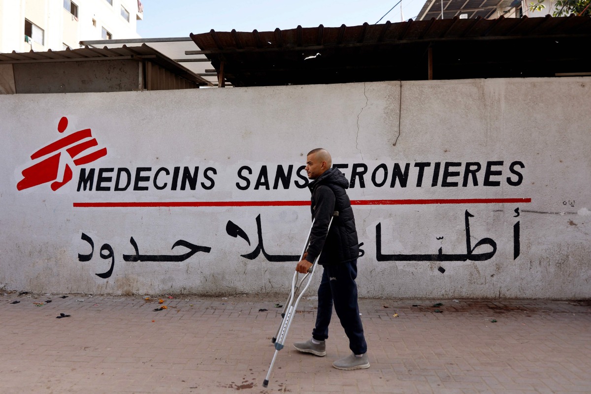 (FILES) A Palestinian man walks on his crutches to the Doctors Without Borders or Medecins Sans Frontieres (MSF) clinic, in the al-Rimal neighborhood of Gaza City on new year's Eve, December 31, 2025. (Photo by Omar AL-QATTAA / AFP)