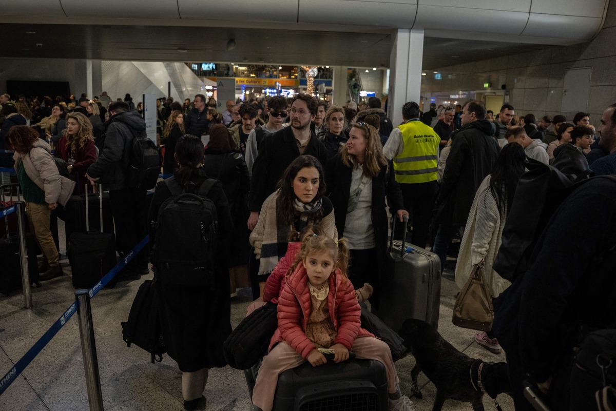 Passengers queue and wait with luggage at a departure hall of Athens' Eleftherios Venizelos international airport in Spata near Athens, on January 4, 2025.  (Photo by Angelos TZORTZINIS / AFP)
