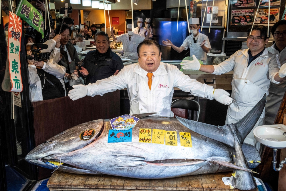 Kiyoshi Kimura (C), president of Kiyomura Corp., the Tokyo-based operator of sushi restaurant chain Sushizanmai, displays a 243-kilogram bluefin tuna at his main restaurant in Tokyo on January 5, 2026, after the New Year's auction at Toyosu fish market. (Photo by Yuichi Yamazaki / AFP)
 