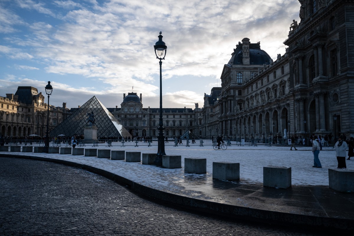 This photograph shows a general view of the Louvre Museum, with the Louvre pyramid (L) designed by Chinese-US architect Ieoh Ming Pei, after the first snowfall of the year in Paris on January 3, 2026. (Photo by Blanca CRUZ / AFP)