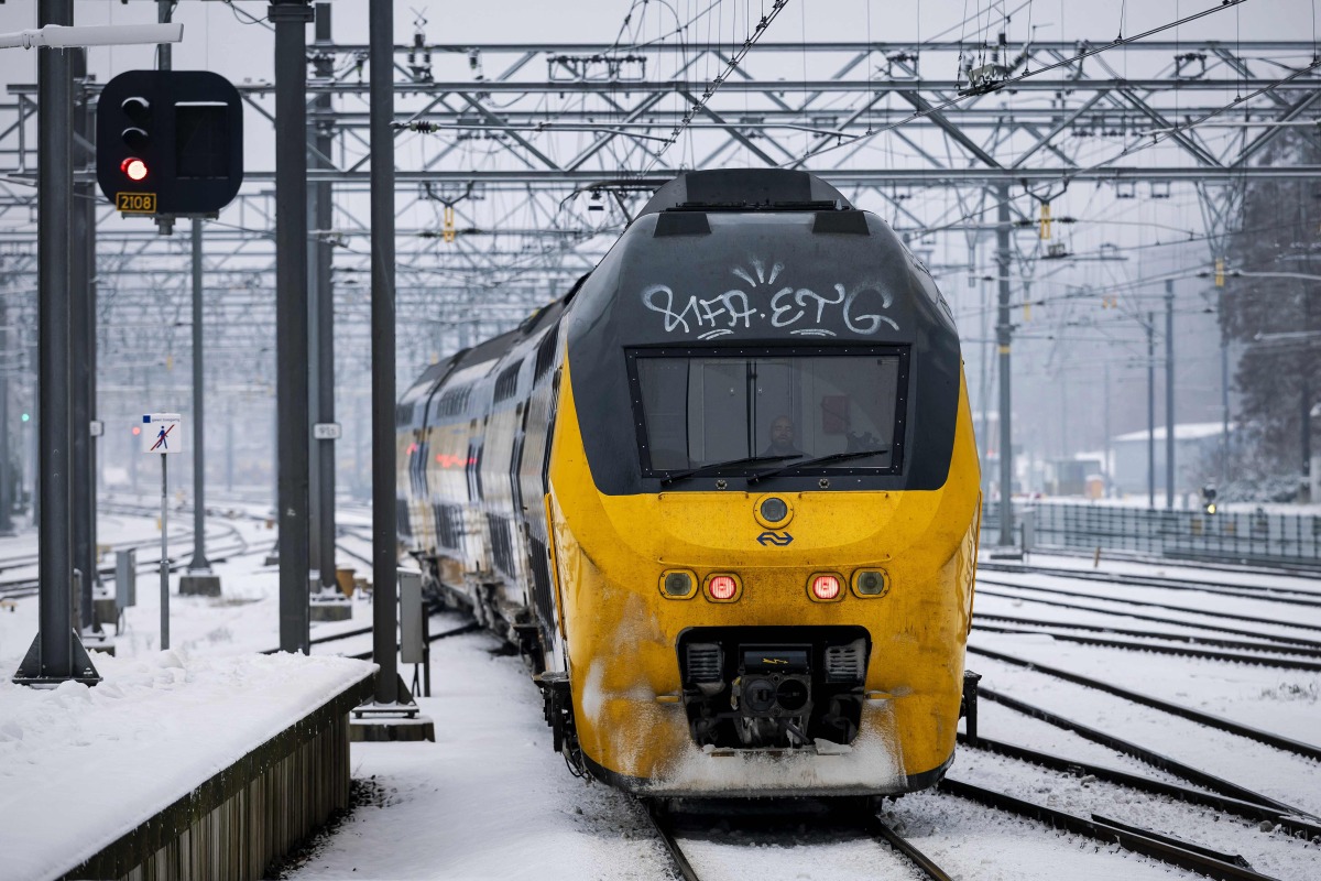 A train moves along a platform covered in snow, at Arnhem Central Station, as train service is resuming after an IT outage at the Dutch national railway service Nederlandse Spoorwegen (NS), on January 6, 2026. (Photo by Robin van Lonkhuijsen / ANP / AFP)