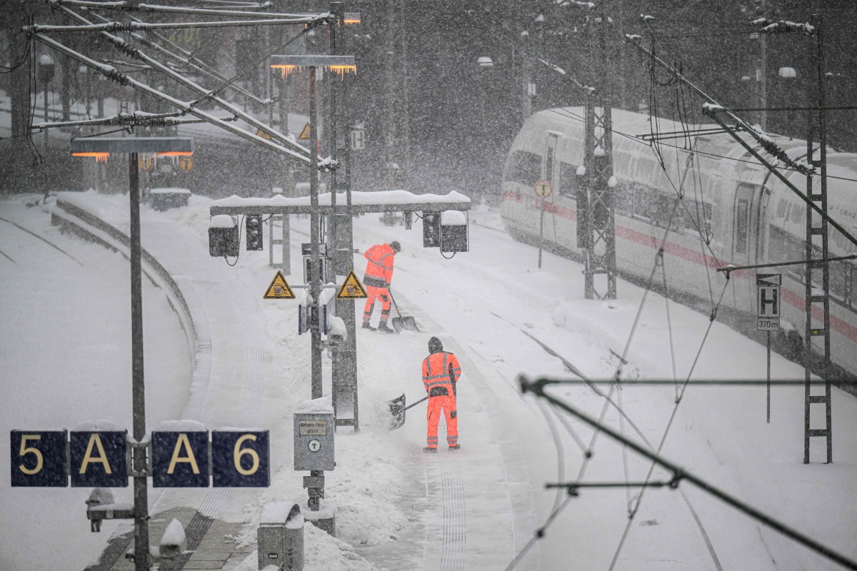 Workers clear the snow from the platforms at Hamburg main railway station in Hamburg, Germany, on January 9, 2026 (Photo by DANIEL REINHARDT / AFP)