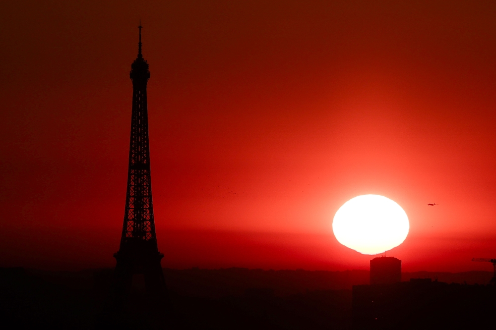 (Files) The sun rises by the Eiffel Tower in Paris on July 1, 2025. (Photo by Thibaud Moritz / AFP)
 