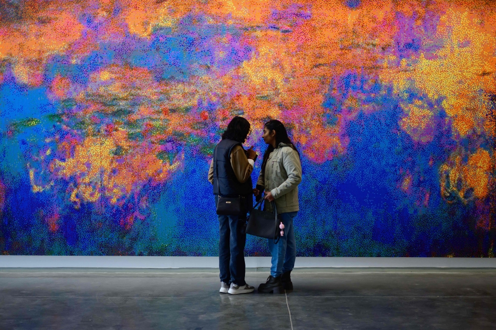 Visitors look at an artwork titled 
