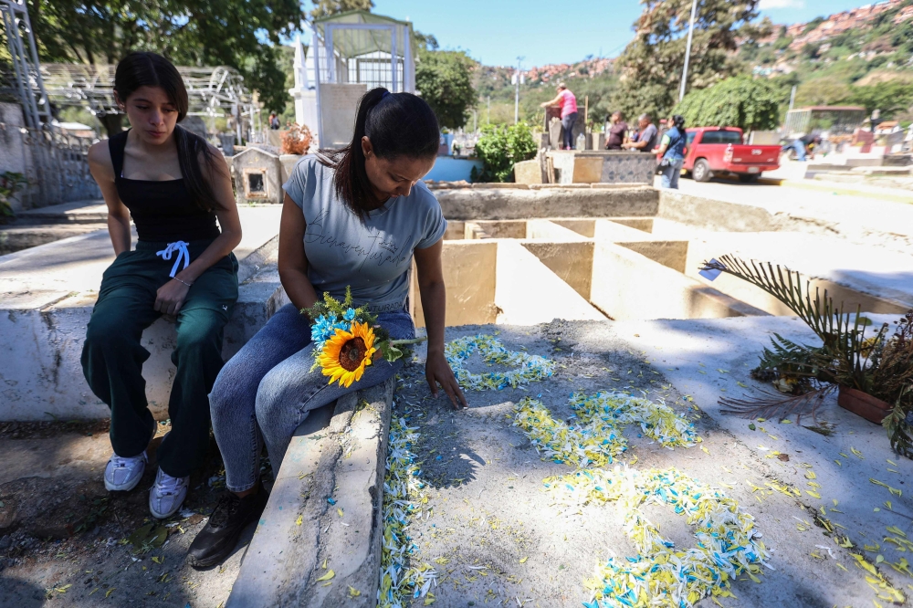 Natividad Martinez (R), mother of private Saul Pereira, visits his grave at the General Cemetery of the South in Caracas on January 18, 2026. (Photo by Pedro Mattey / AFP)