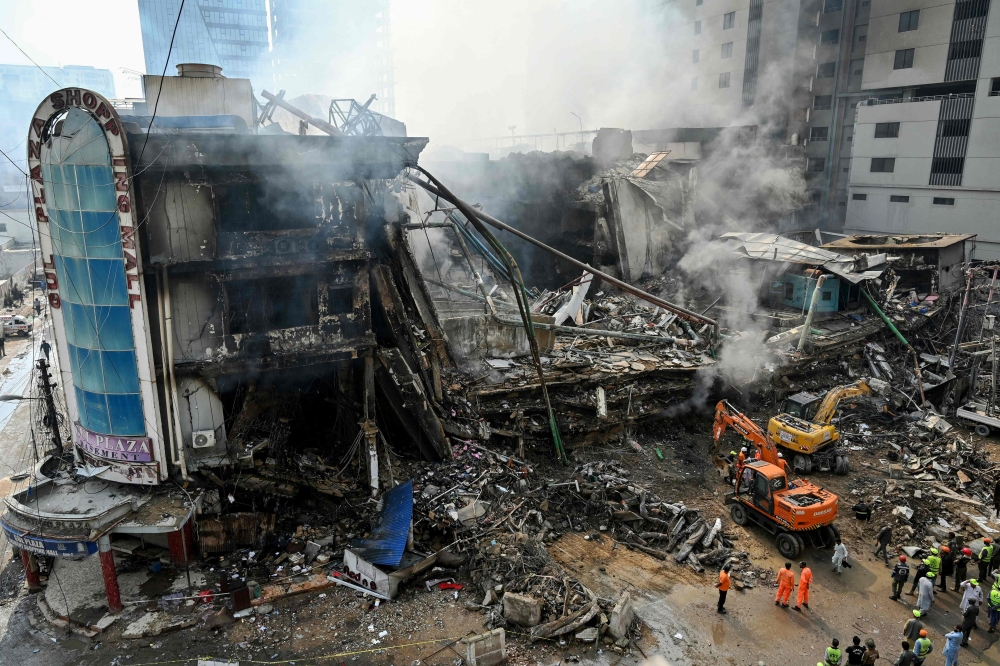 Rescue workers search amid the debris using excavators after a massive fire at a shopping mall in Karachi on January 19, 2026. (Photo by Asif Hassan / AFP)