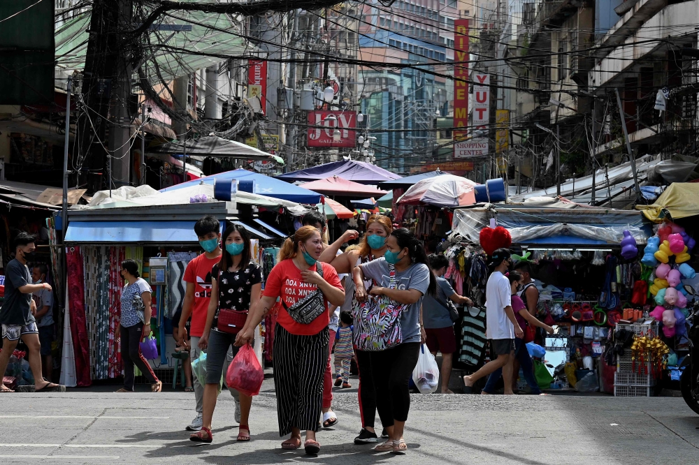 Pedestrians walk as they shop at a market in Manila on January 26, 2022. (Photo by JAM STA ROSA / AFP)