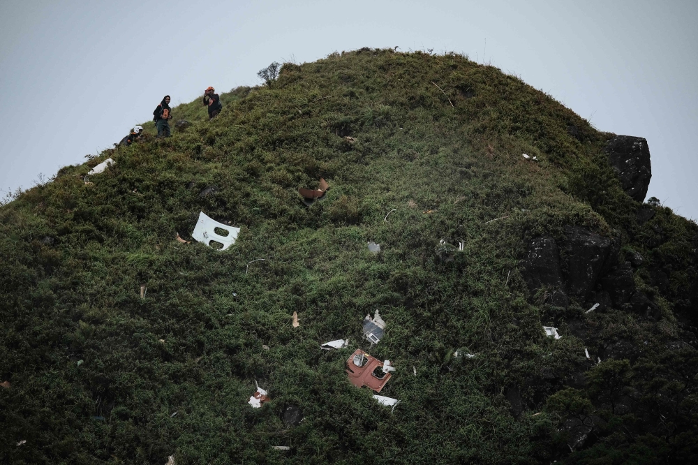 Search and rescue personnel prepare to carry the wreckage of an Indonesian Air Transport turboprop aircraft, a day after it crashed while en route from Yogyakarta to Makassar, at Mount Bulusaraung in South Sulawesi on January 18, 2026. (Photo by Muchtamir Zaide / AFP)