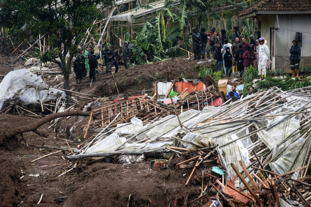 Rescuers search for victims buried by a landslide in Pasirlangu village, Bandung, West Java, on January 24, 2026, after Indonesia National Search and Rescue Agency (BASARNAS) said eight people were killed and 82 remain missing when the landslide struck early Saturday. (Photo by Timur Matahari / AFP)