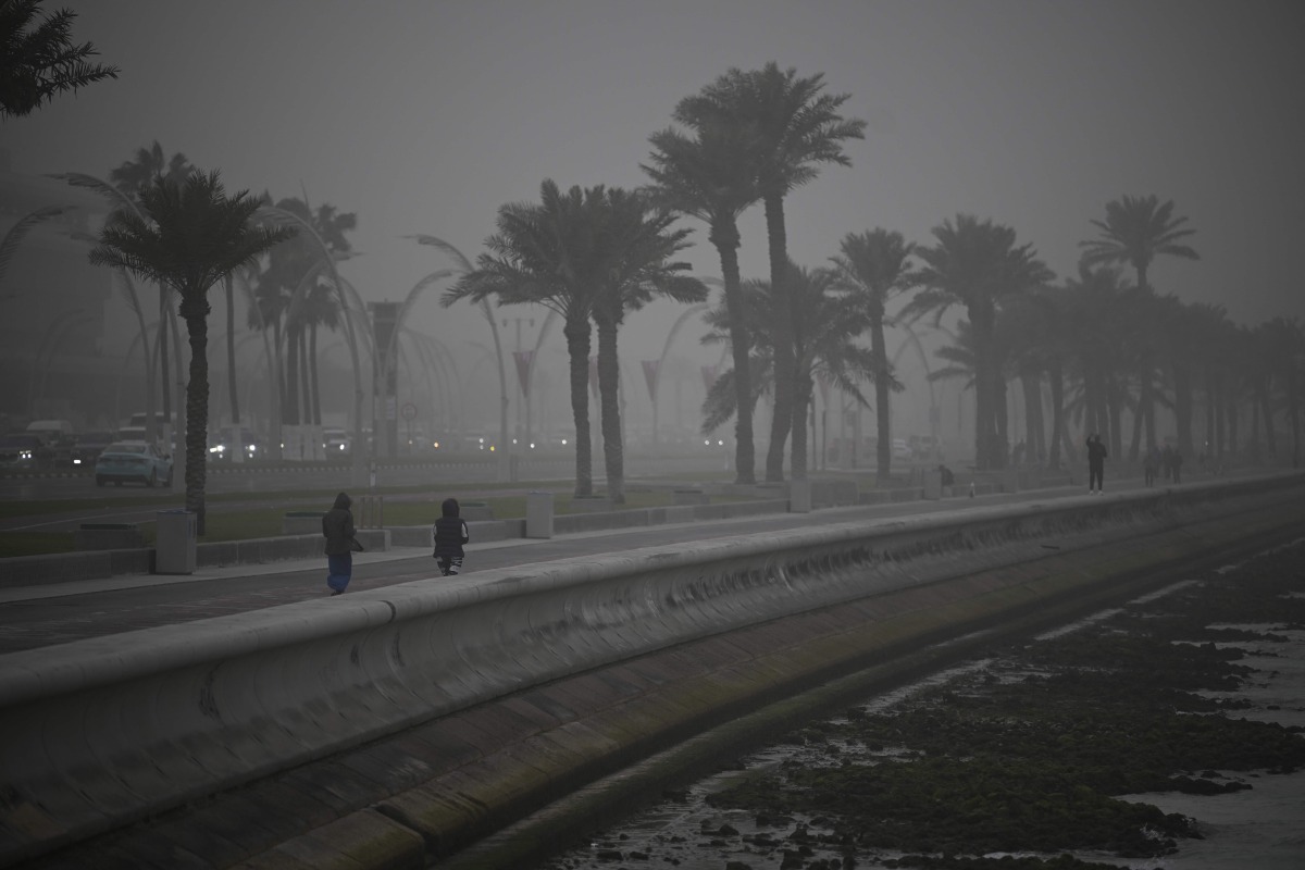 People dressed in winter clothes take a stroll as strong northwesterly winds brought temperatures down in Qatar yesterday.