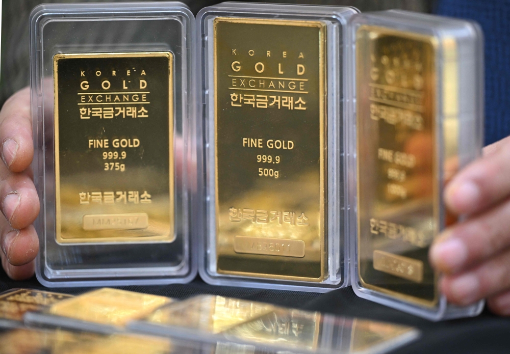 An employee displays gold bars at a store of the Korea Gold Exchange in Seoul on January 26, 2026. (Photo by Jung Yeon-je / AFP)