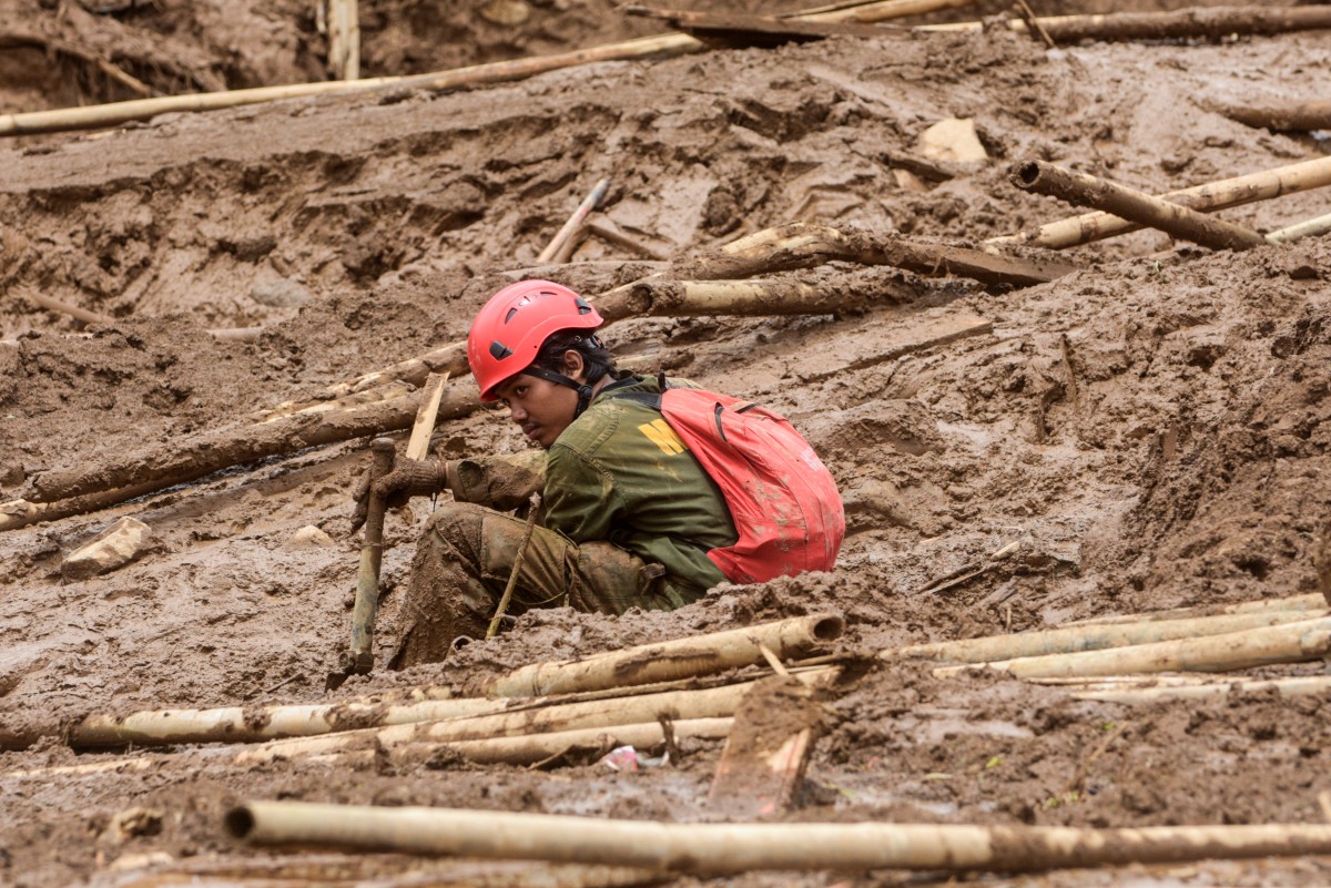A rescuer rests as they search for victims buried by a landslide in Pasirlangu village in Cisarua, Bandung, West Java, on January 26, 2026. Photo by Timur Matahari / AFP
