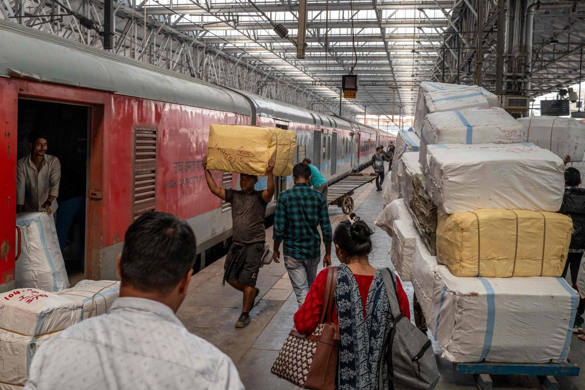 Passengers walk past a cargo compartment on a long-distance train platform at the Chhatrapati Shivaji Maharaj Terminus (CSMT) in Mumbai on February 1, 2026. (Photo by Punit PARANJPE / AFP)