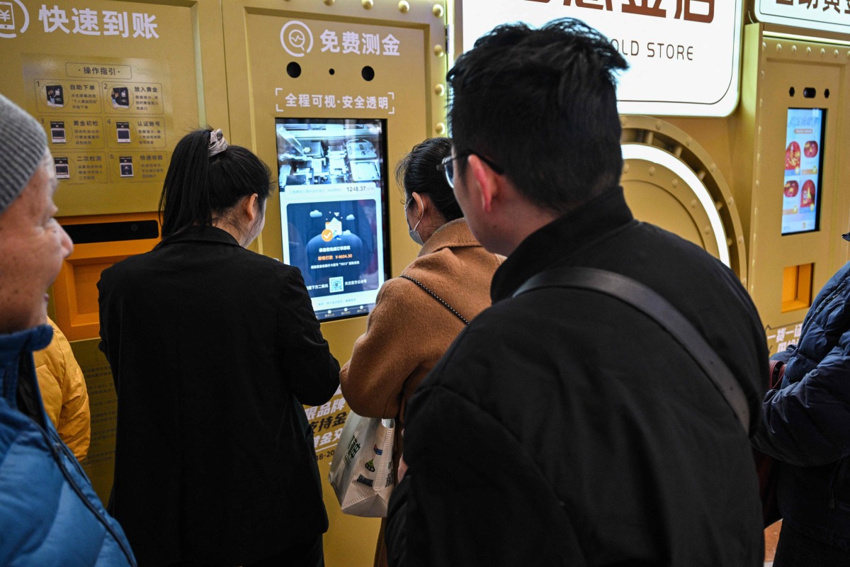 Customers wait to sell their gold jewelry in a Smart Gold Store Machine placed in a shopping mall in Shanghai on January 29, 2026. (Photo by Hector RETAMAL / AFP) 