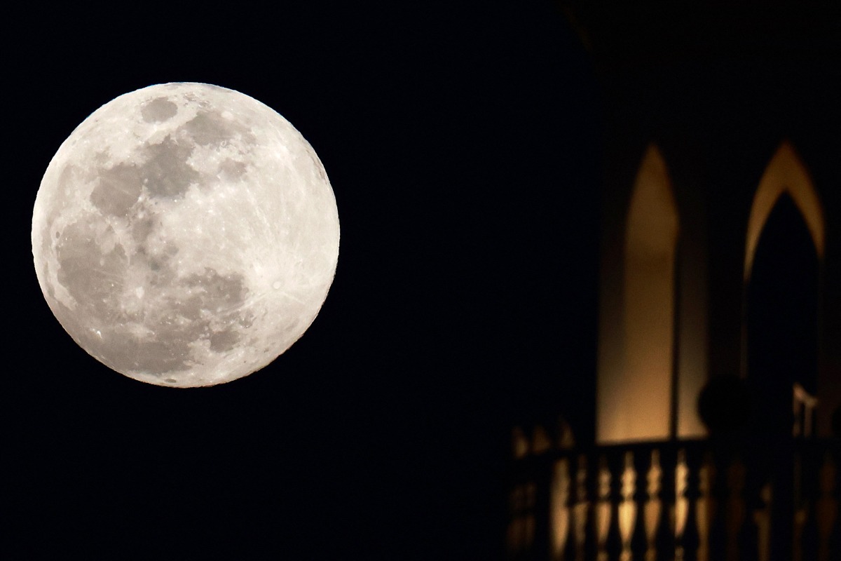 The full moon rises behind a mosque in Doha on February 1, 2026. (Photo by Karim JAAFAR / AFP)