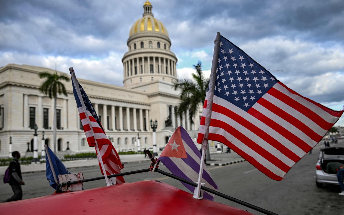 Two US flags and a Cuban flag flutter on the roof of a tricycle in front of the Capitolio in Havana on February 3, 2026. (Photo by YAMIL LAGE / AFP)