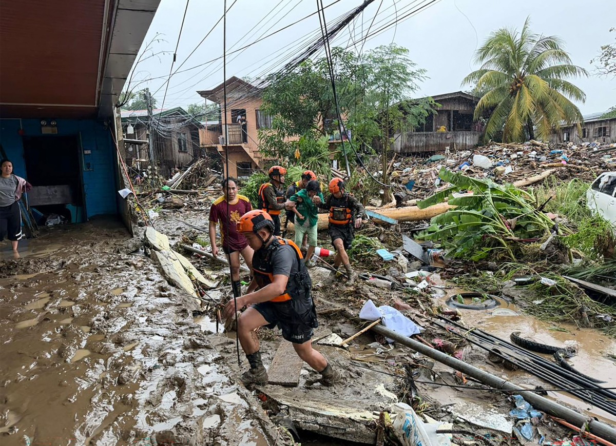 Rescuers evacuate a woman after Tropical Storm Penha hit the area in Iligan, Lanao del Norte province on February 6, 2026. (Photo by Merlyn Manos / AFP)