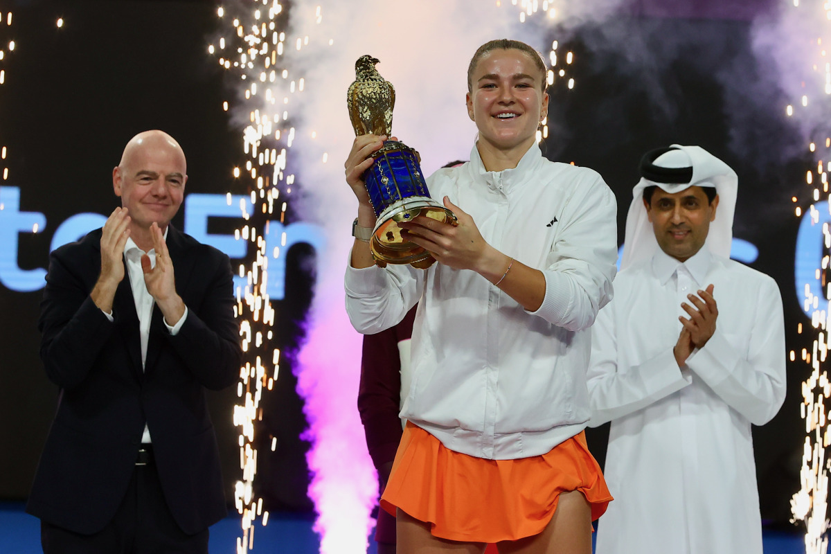 Karolina Muchova celebrates with the winner's trophy. QTSBF President Nasser Al Khelaifi and FIFA President Gianni Infantino are also present.