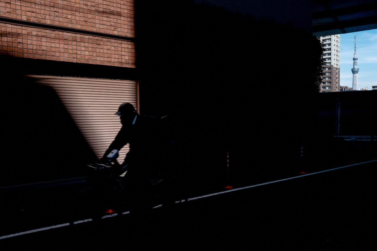A person rides a bicycle as the Tokyo Skytree is seen in the background in Tokyo on February 10, 2026. (Photo by Philip FONG / AFP)