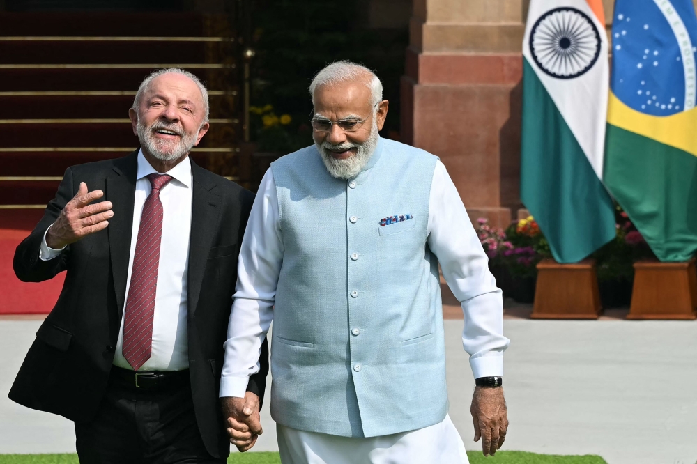 India's Prime Minister Narendra Modi (R) holds hands with Brazil's President Luiz Inacio Lula da Silva as they walk before their meeting at the Hyderabad House in New Delhi on February 21, 2026. (Photo by Sajjad Hussain / AFP)