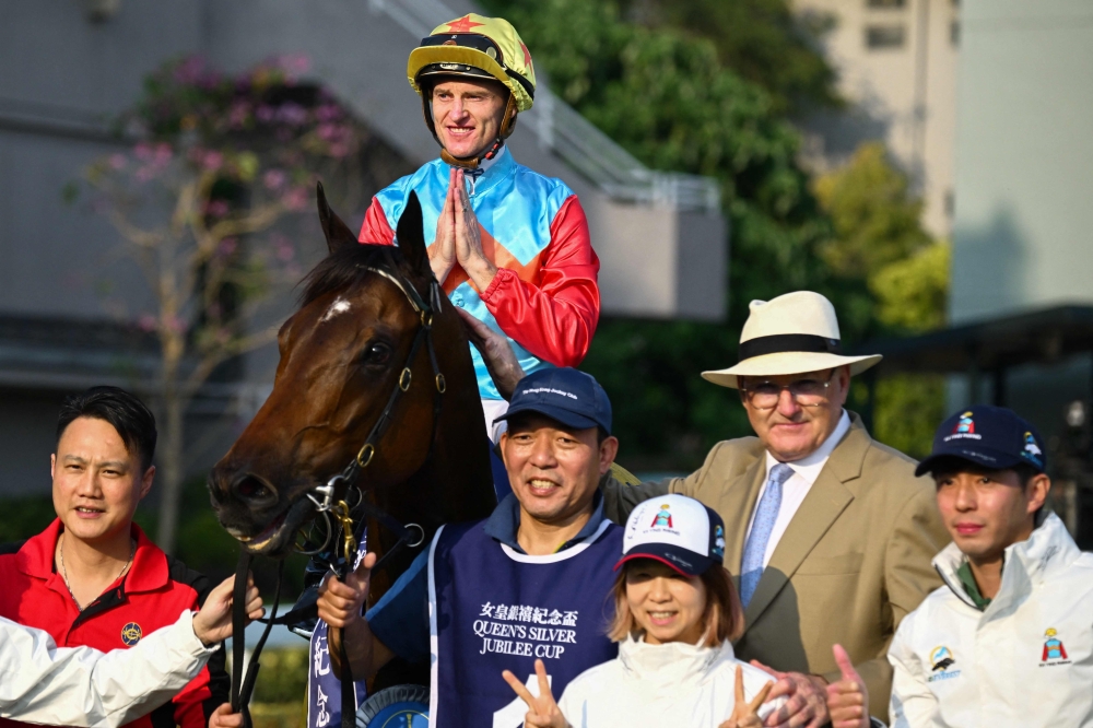 Ka Ying Rising with jockey Zac Purton and trainer David Hayes (2nd R) pose with others after victory in the Queen's Silver Jubilee Cup horse race at Sha Tin Racecourse in Hong Kong on February 22, 2026. (Photo by Peter Parks / AFP)