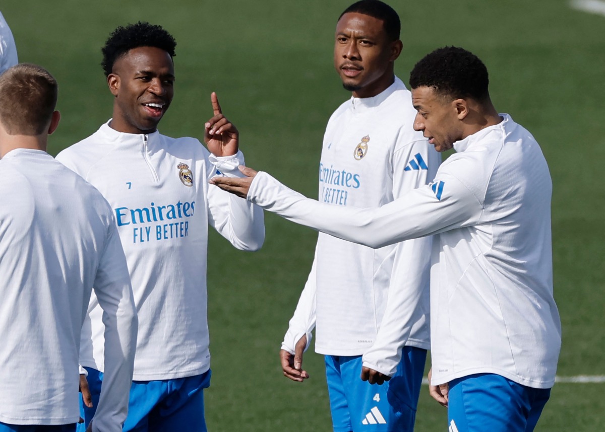 Real Madrid's Brazilian forward #07 Vinicius Junior (L) talks with Real Madrid's French forward #10 Kylian Mbappe (R) during a training session on the eve of their UEFA Champions League knockout round play-off second leg football match against SL Benfica at Santiago Bernabeu Stadium at Real Madrid Sports City in Valdebebas, in the outskirts of Madrid on February 24, 2026. (Photo by Oscar DEL POZO / AFP)