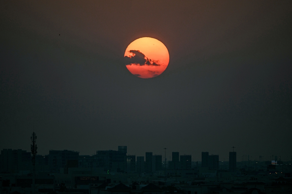 The sun sets over Qatar's capital Doha on February 28, 2026. (Photo by Mahmud Hams / AFP)
 