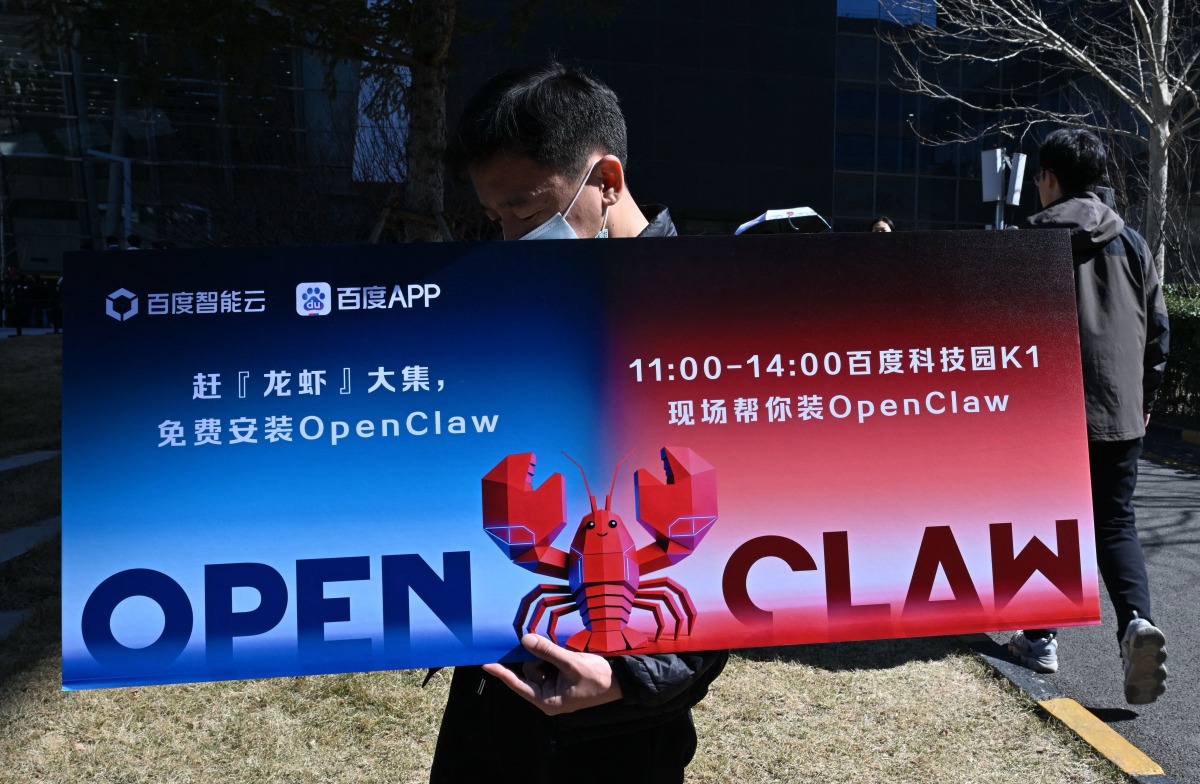 A man holds a placard featuring OpenClaw, an open-source AI assistant, during an event at the Baidu headquarters in Beijing on March 11, 2026. Photo by ADEK BERRY / AFP